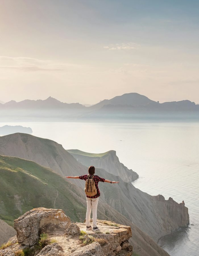 A young Asian woman with a backpack hiking in the summer.